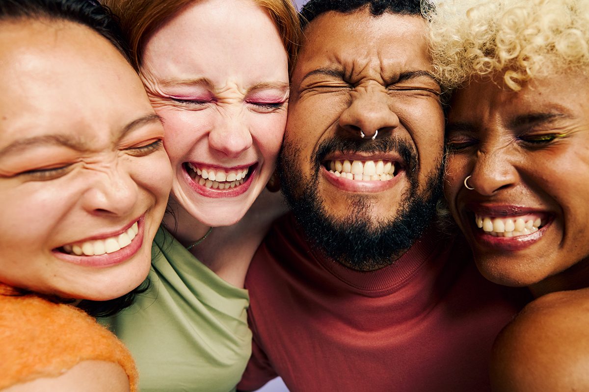 A close-up of four friends embracing and smiling