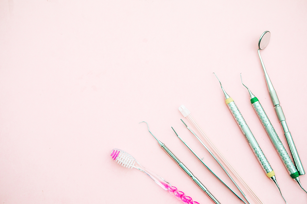 A toothbrush and dental equipment on a pink background