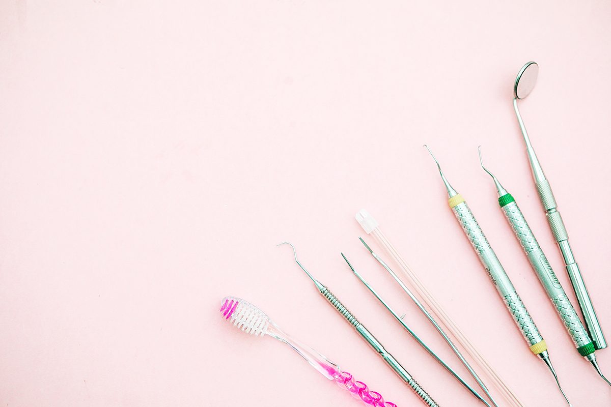 A toothbrush and dental equipment on a pink background