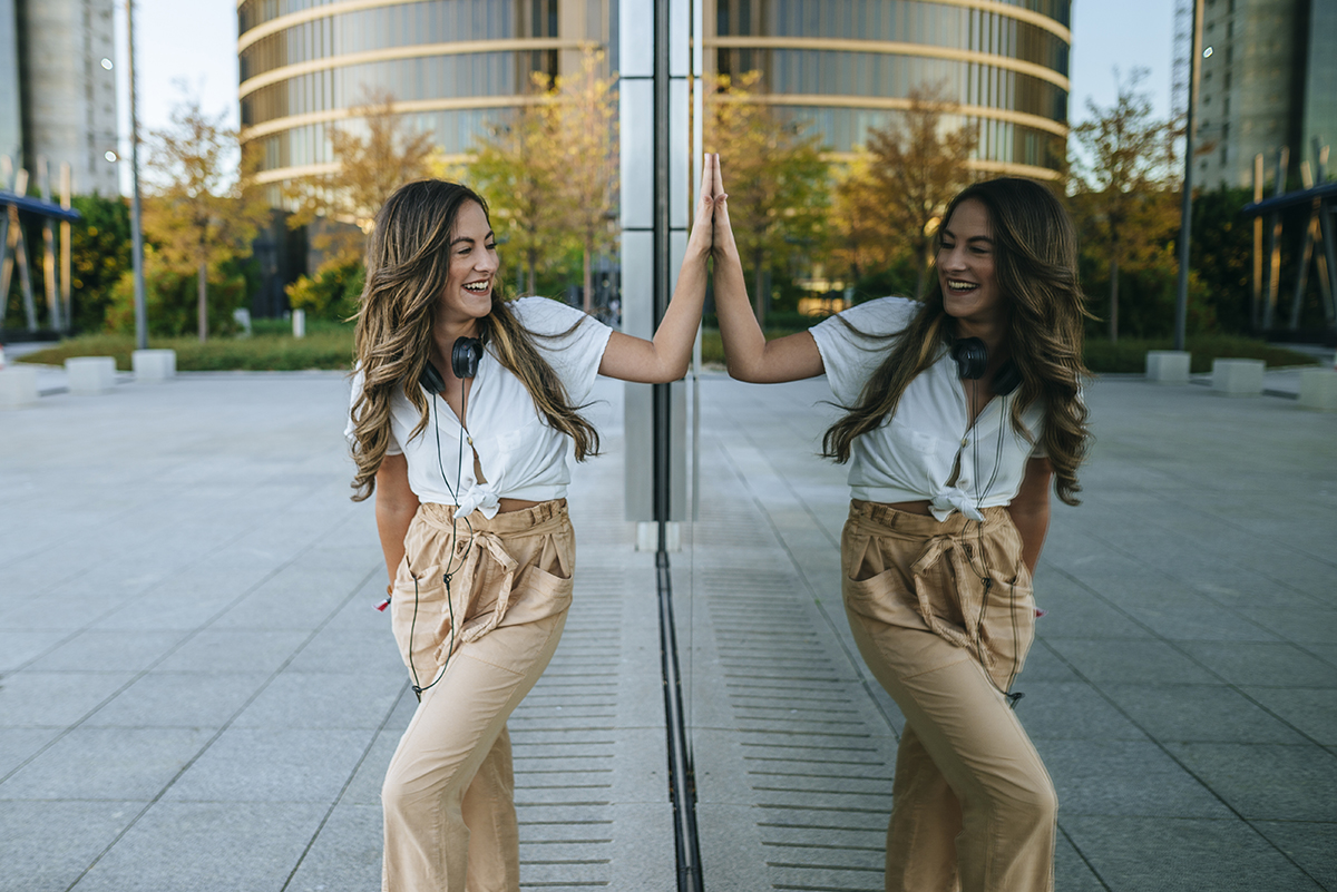 A woman smiling at her reflection in a building window