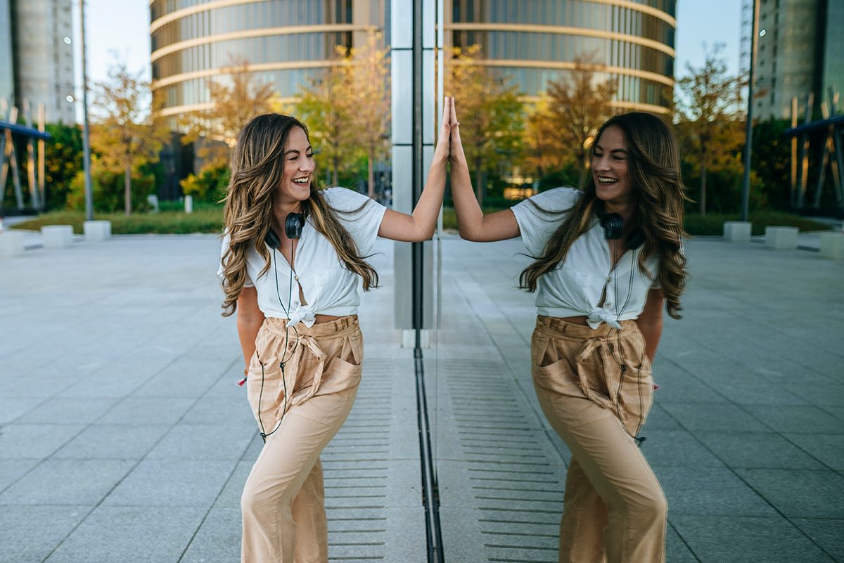 A woman smiling at her reflection in a building window