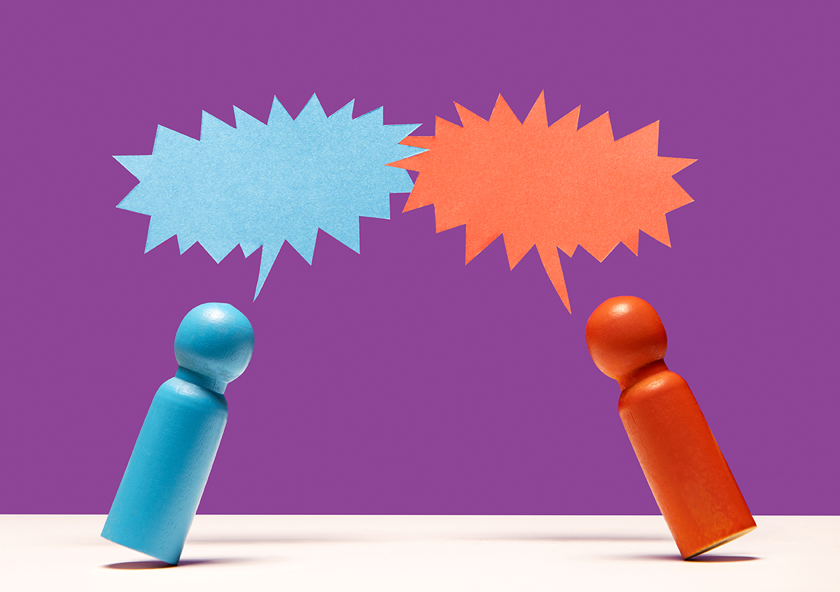 A blue and red wooden figurine with speech bubbles between them against a purple background