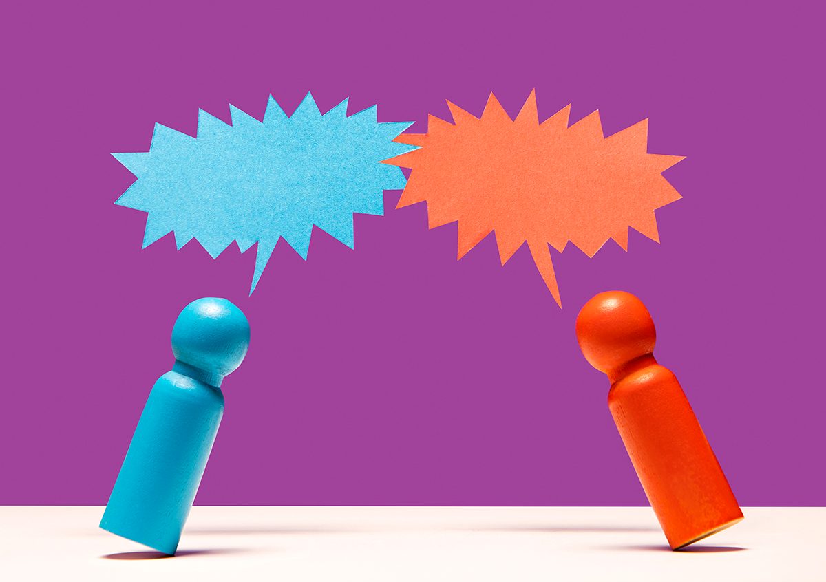 A blue and red wooden figurine with speech bubbles between them against a purple background