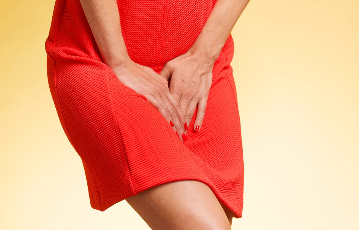 A cropped shot of a woman in a red dress against a yellow background, visibly needing the toilet