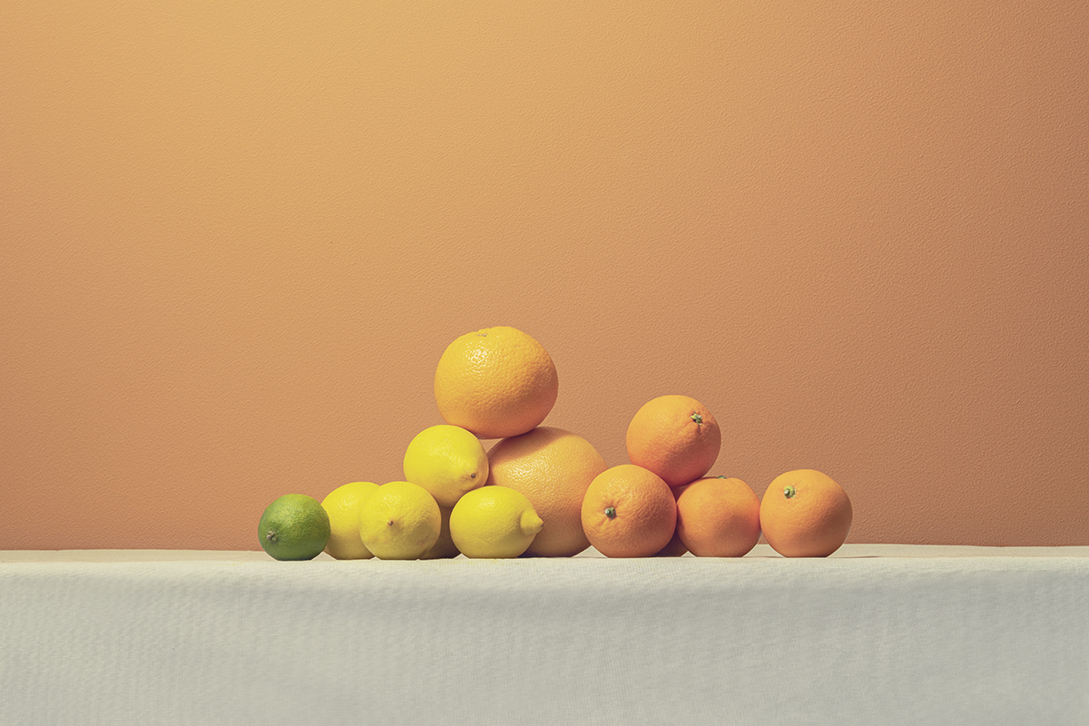 A pile of citrus fruits against an orange background.