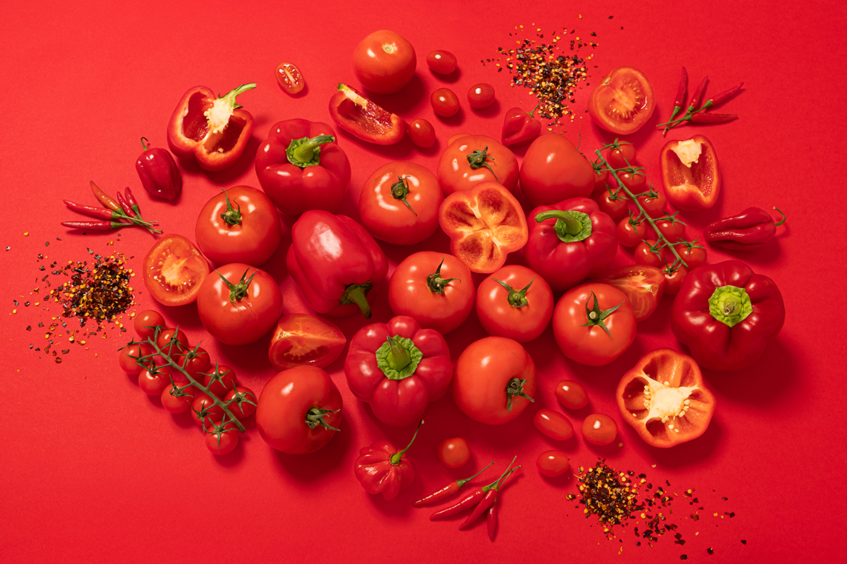 A top view of a group of red vegetables on a red background.