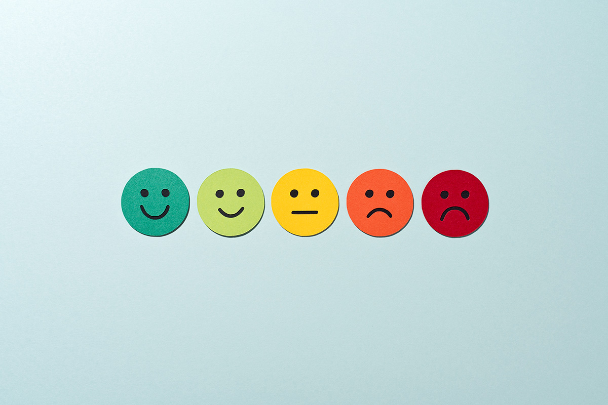 A row of smiley faces, made from paper, ranging from happy to sad on a blue background