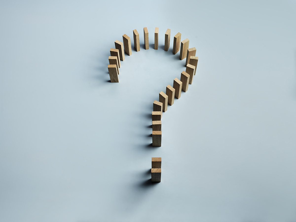 Wooden blocks arranged in the shape of a question mark on a blue background