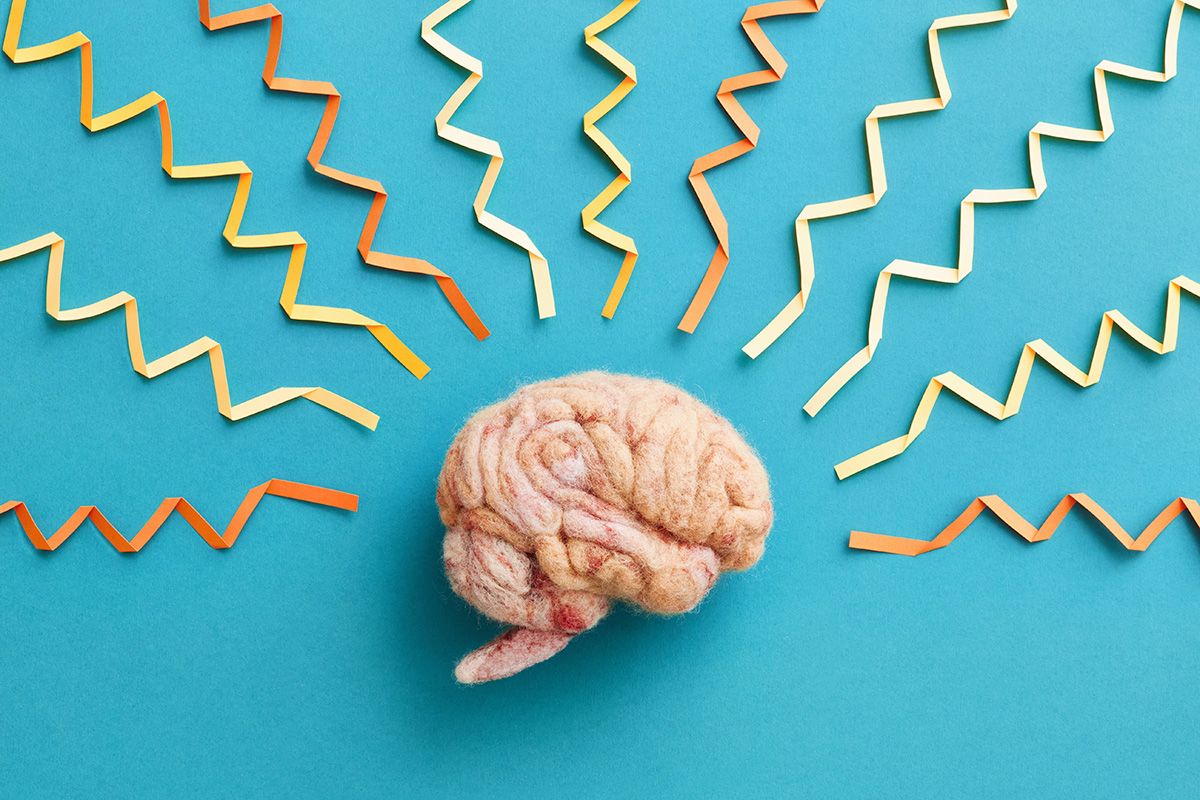 A brain made from wool and brainwaves made from paper on a blue background