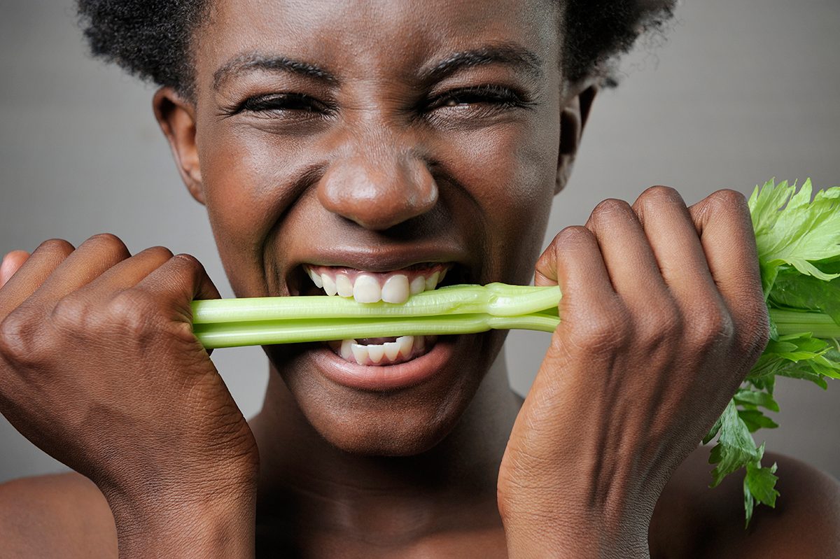 Young woman biting into celery
