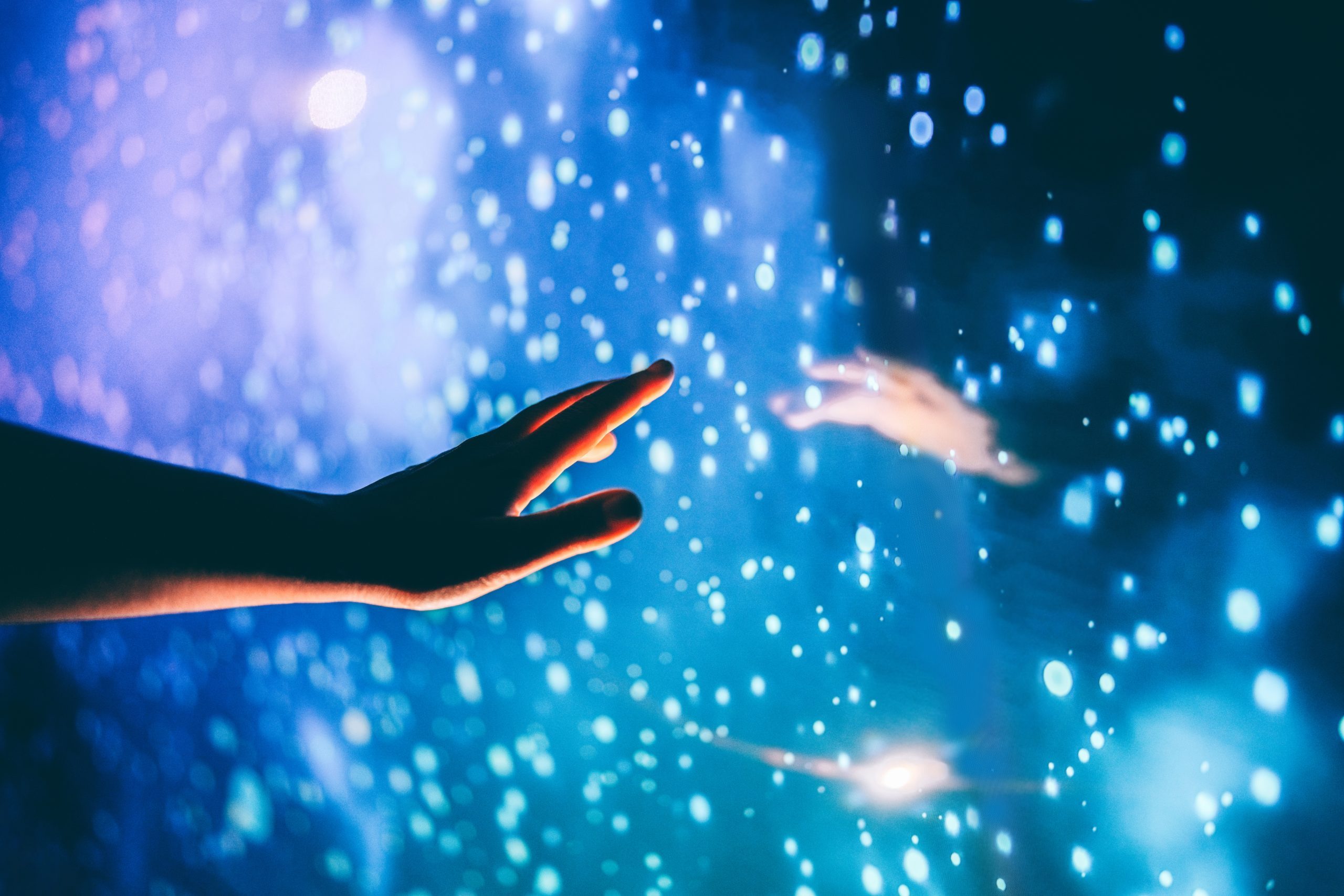 A hand reaching toward an image depicting space
