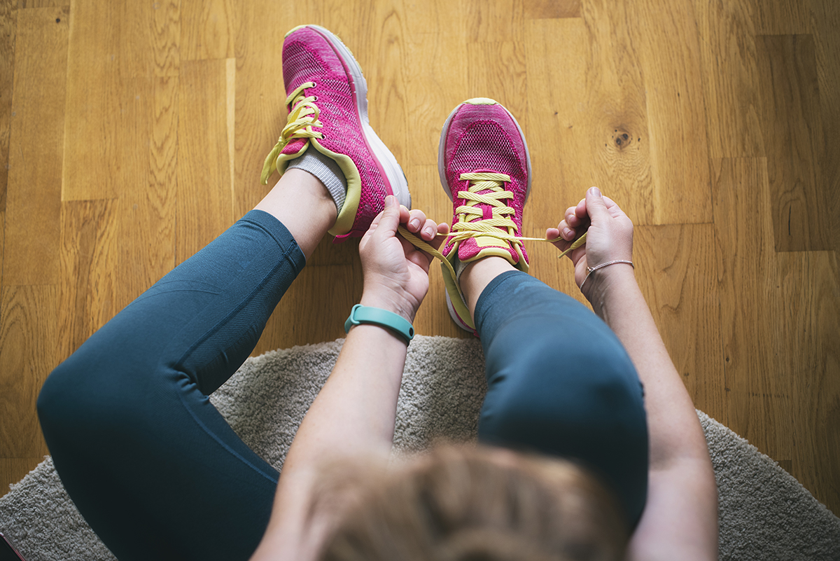 An overhead shot of a woman tying the laces of her running shoes