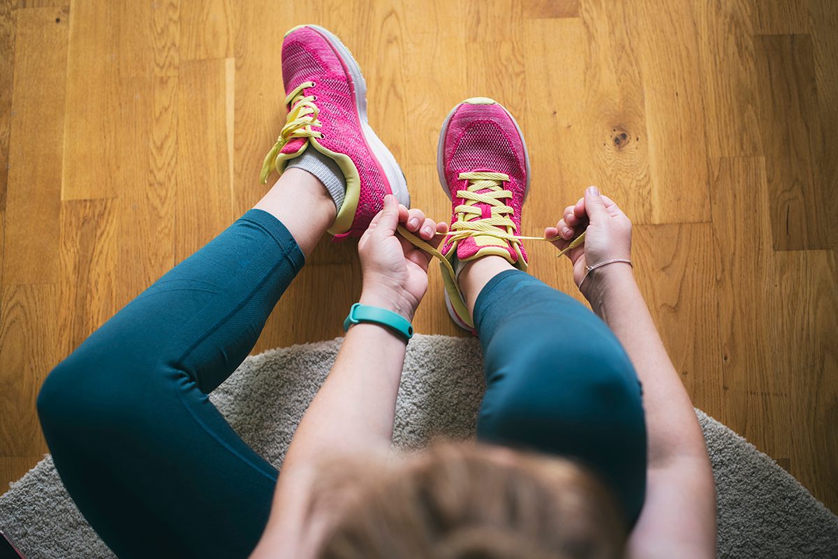 An overhead shot of a woman tying the laces of her running shoes