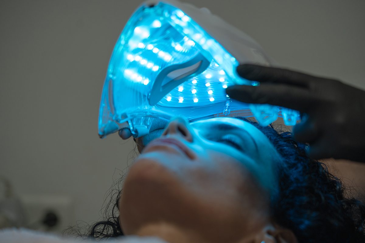 A woman is getting a blue light therapy treatment in a beauty salon