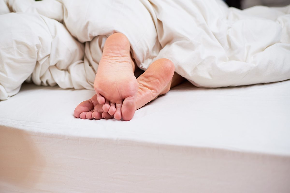 Feet poking out of a white duvet on a bed