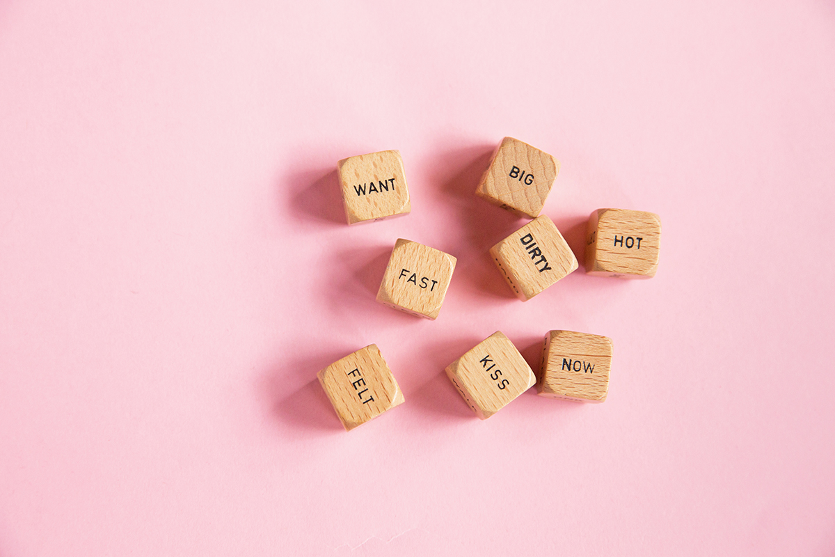 Wooden cubes that have different words written on them against a pink background