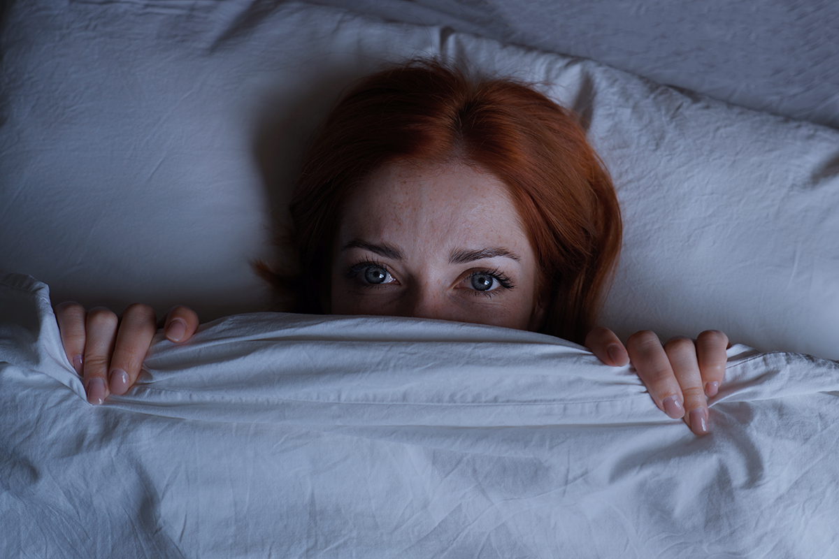 A woman's face is peeking out of a duvet
