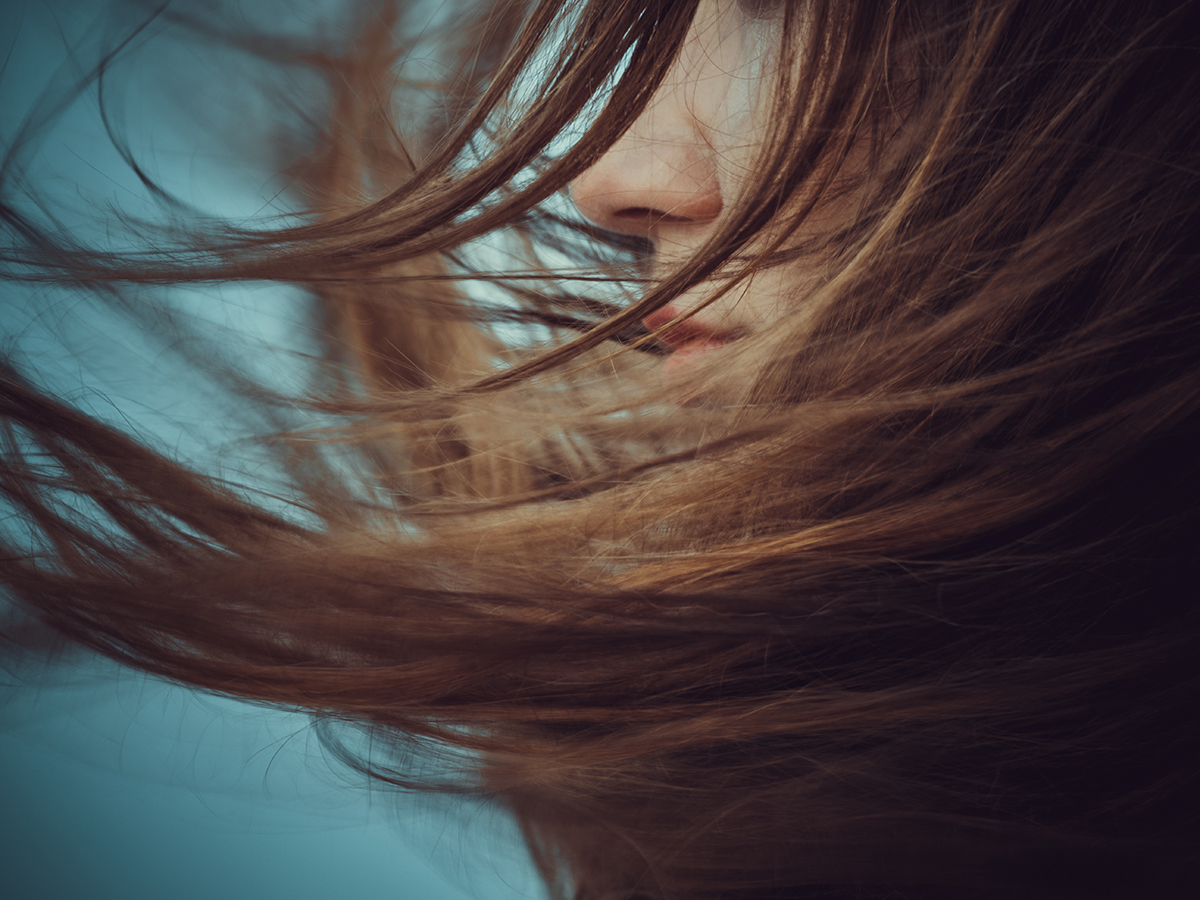 A woman's hair is blowing around her face 