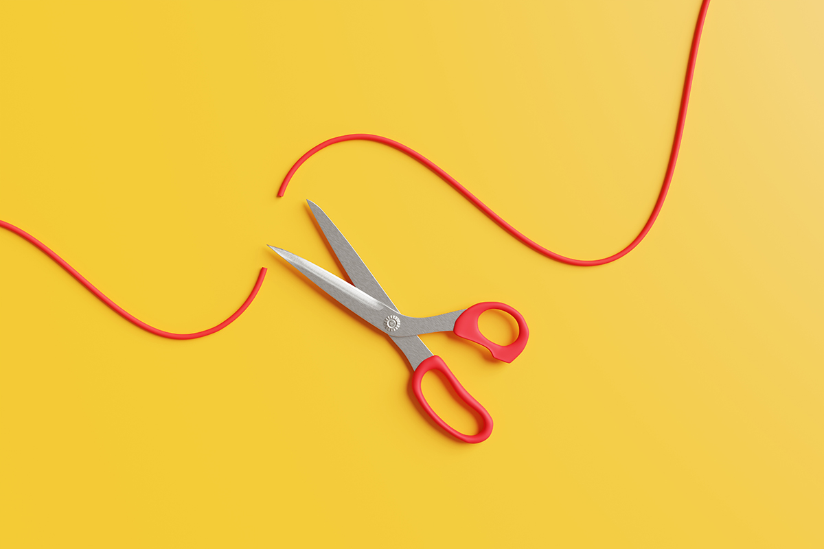Scissors cutting a red string on a yellow background