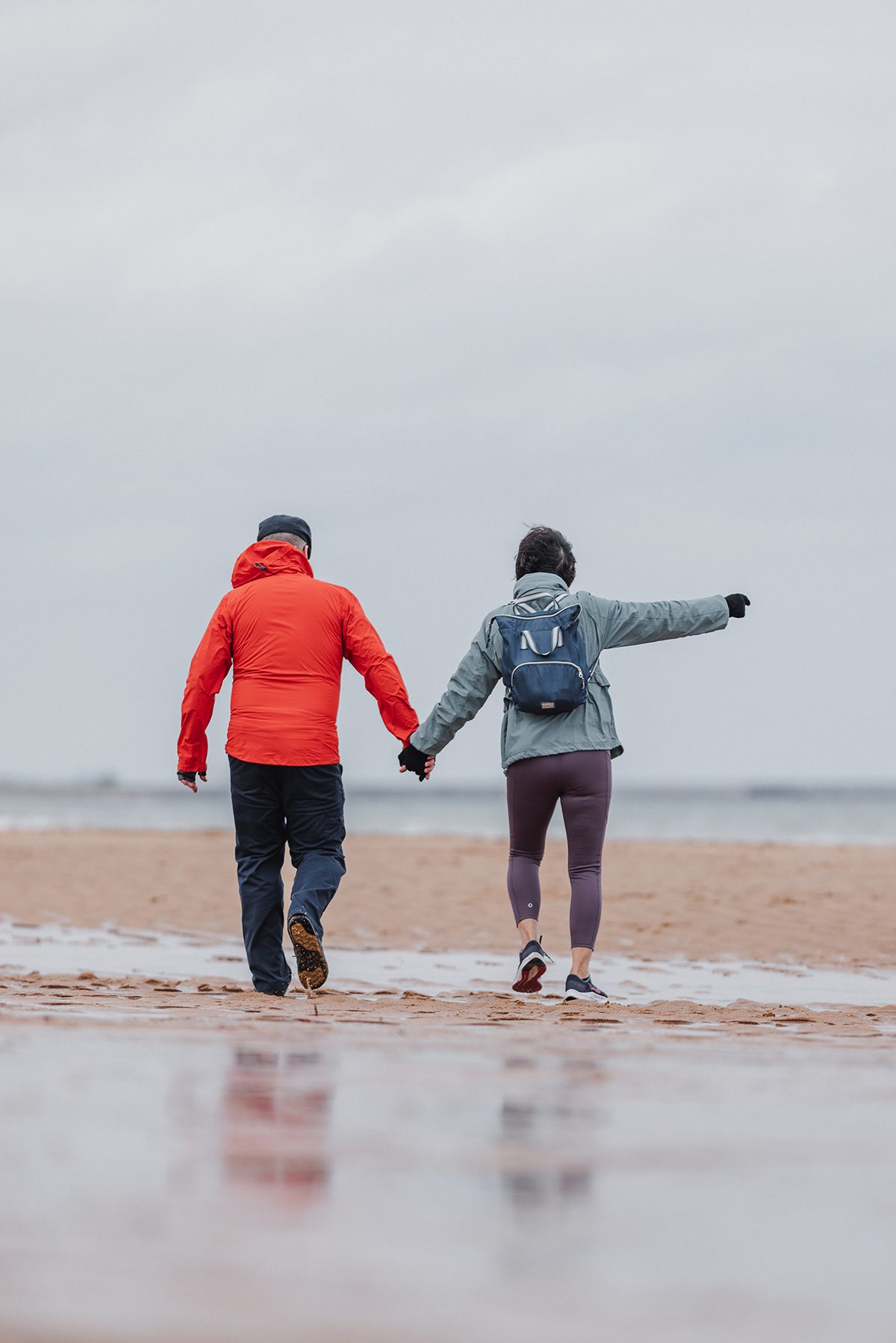 A senior couple walking on a beach holding hands