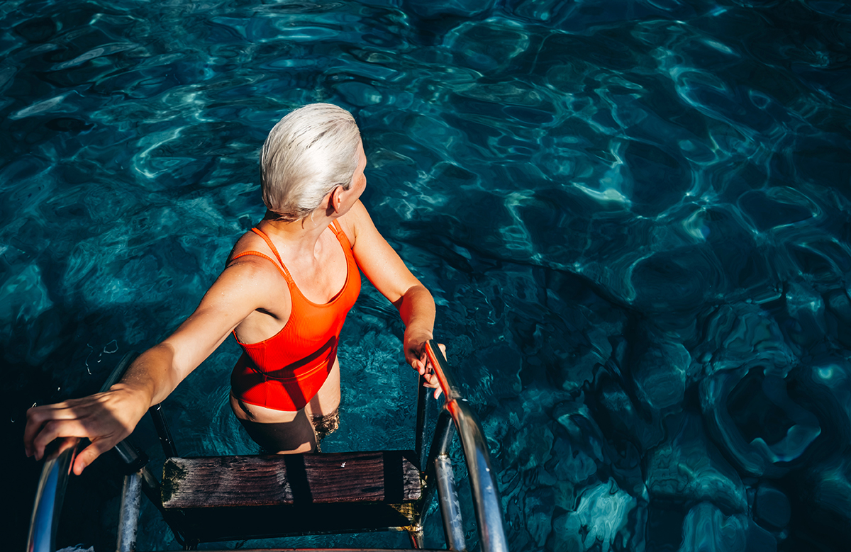 A woman stepping off a ladder into water