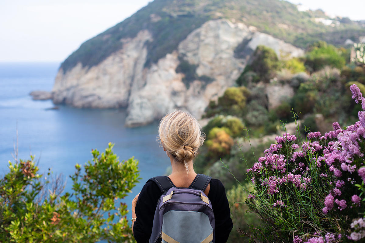 A woman looks out at the sea on a clifftop hike