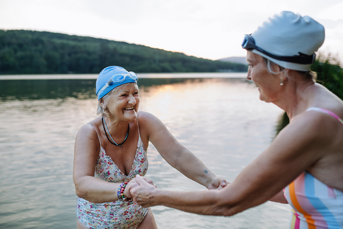Two elderly women standing in a lake holding hands