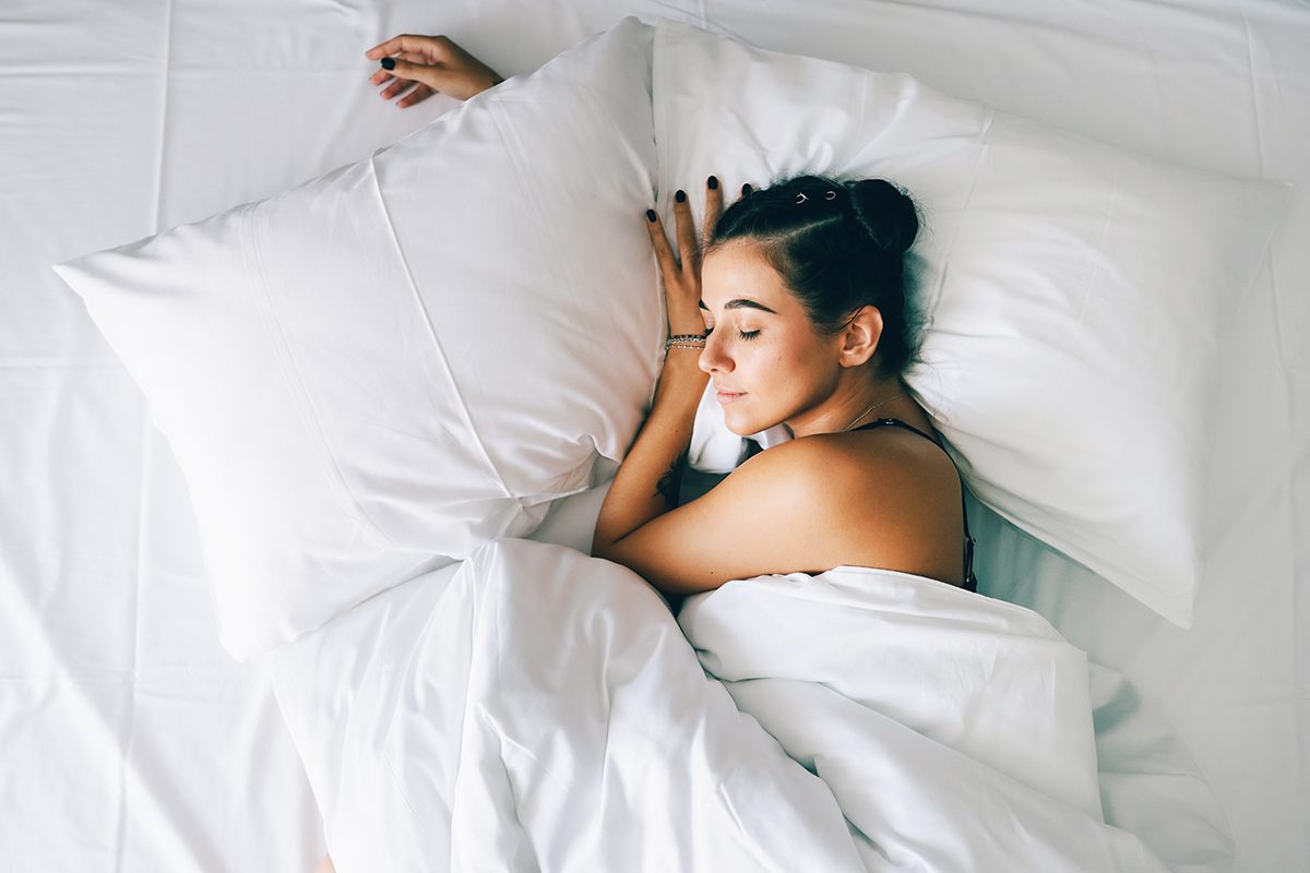 A woman sleeping in a bed with white bedding