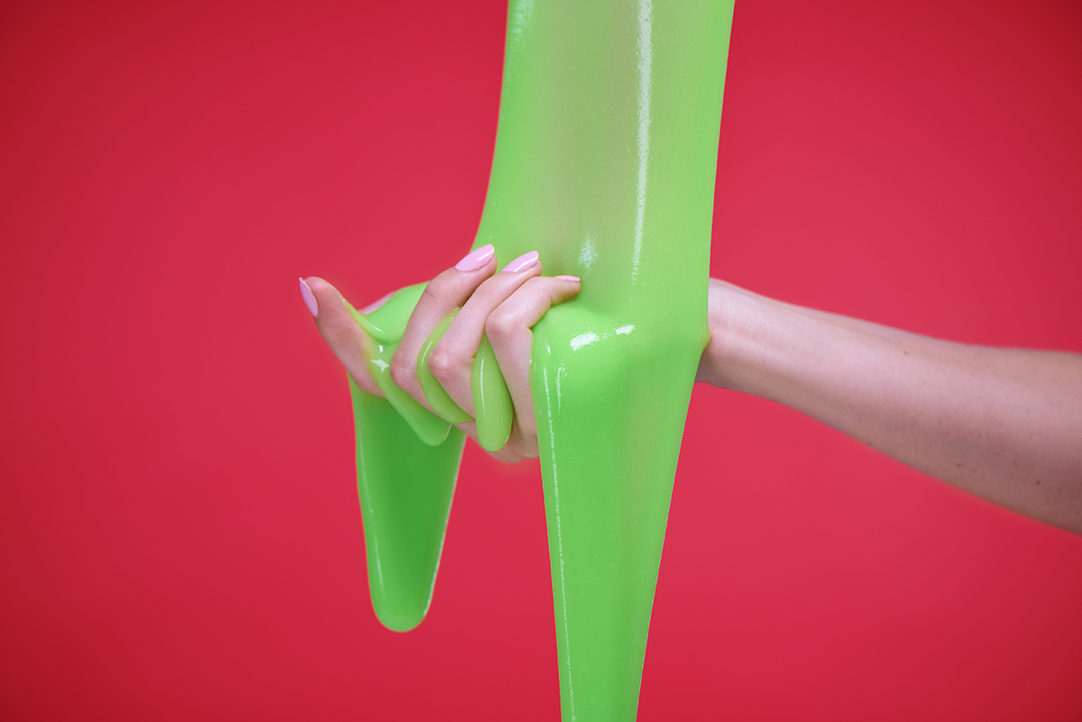 Green slime falls into an outstretched hand on a red background