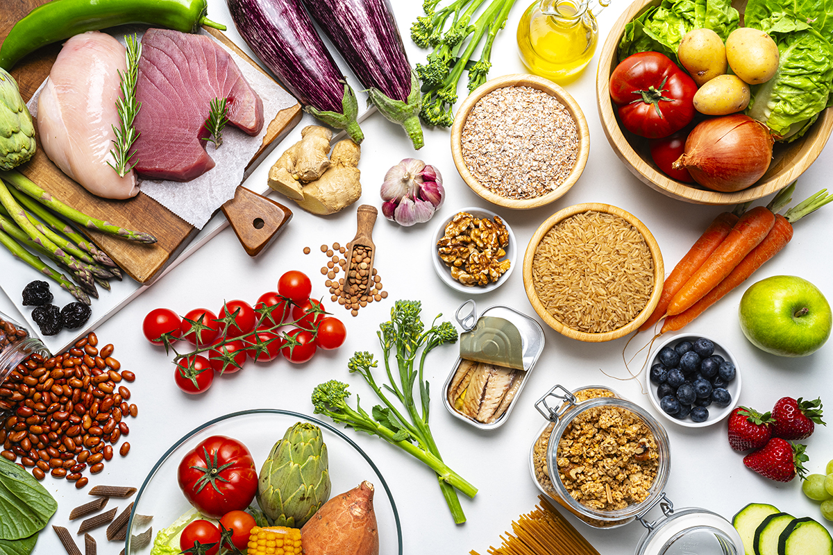 A selection of raw, healthy foods, including meats, vegetables, fruits, carbohydrates and fats.