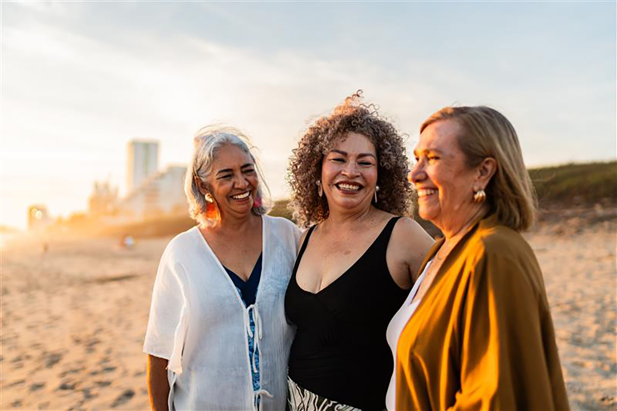 Three smiling women embracing on a beach