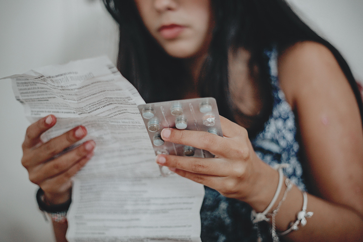 A woman holding contraceptive pills and reading the instructions