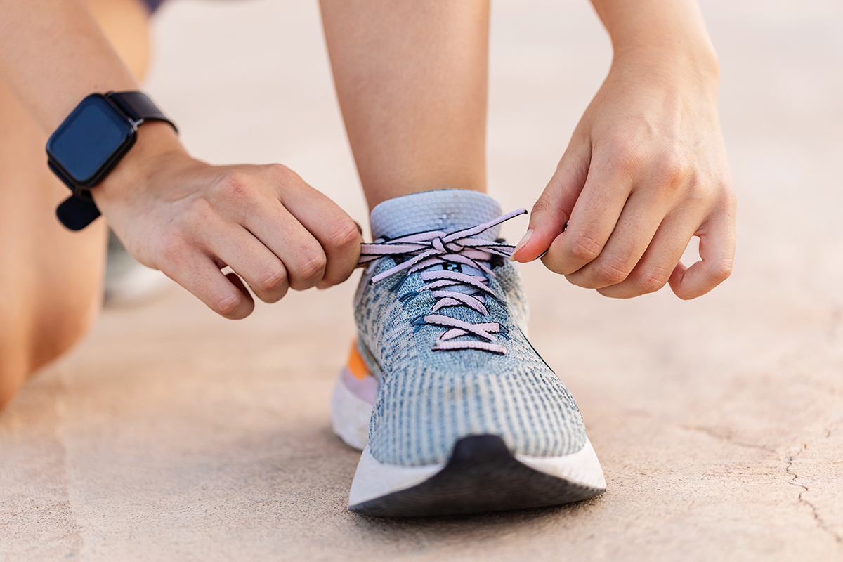 A close-up view of a person tying the laces of their running trainers.