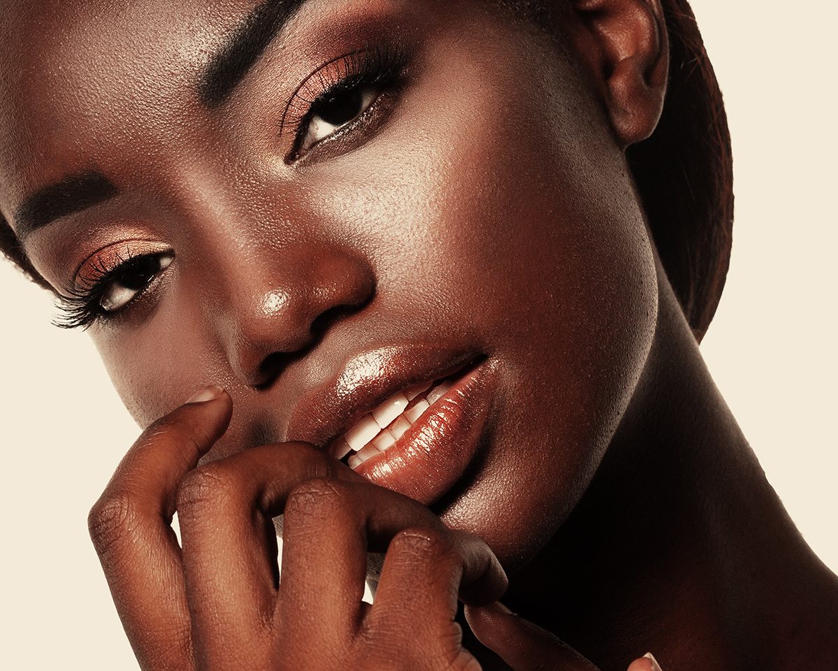 A close-up of a model with her hand gently touching her face