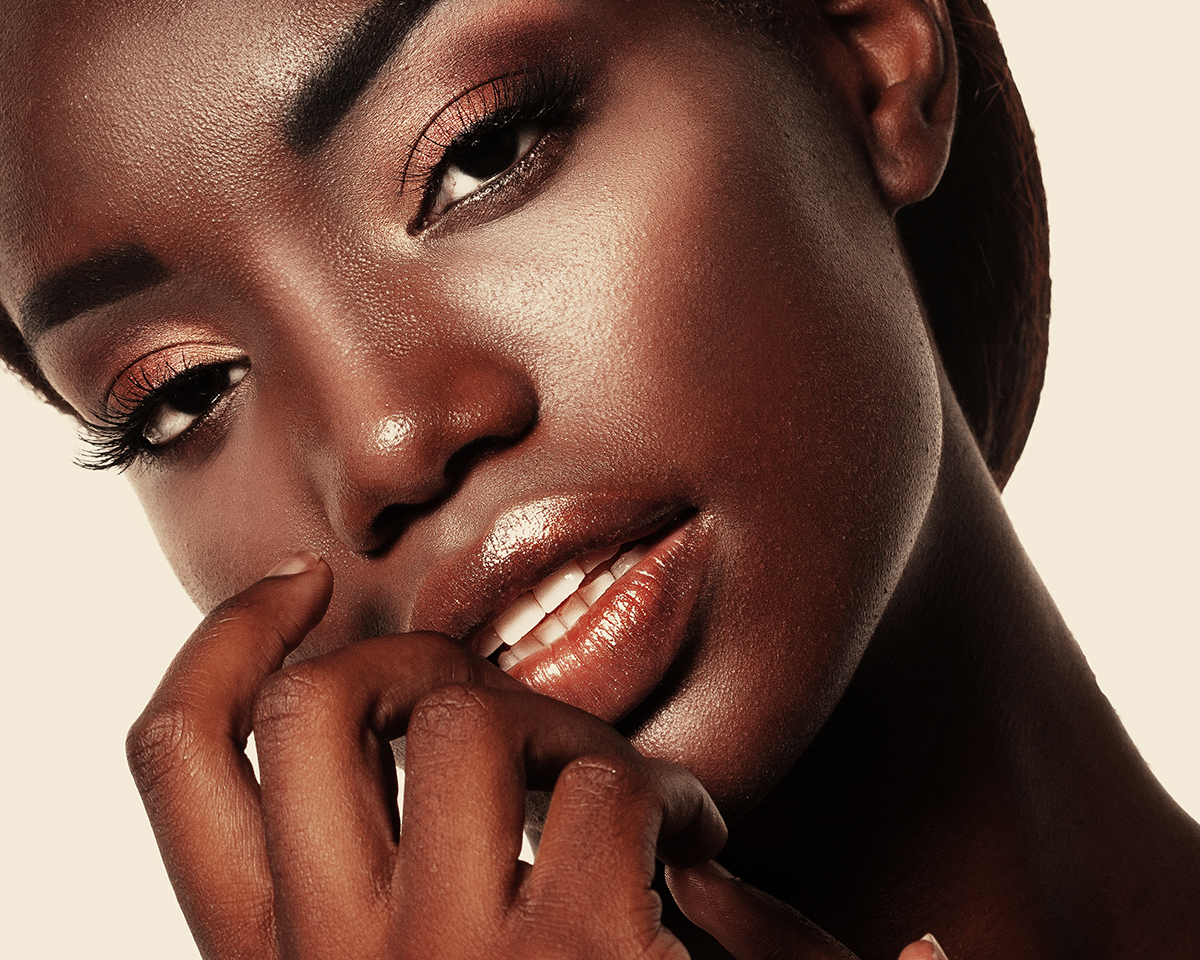 A close-up of a model with her hand gently touching her face