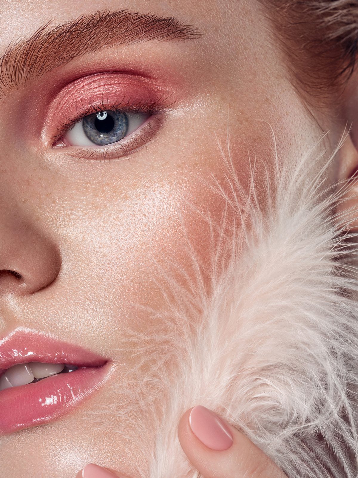 An extreme close-up of a woman holding a feather to her face