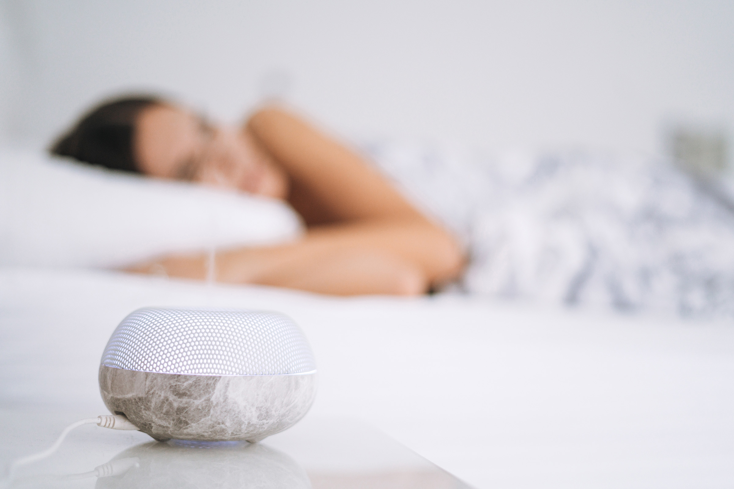 Air humidifier aroma diffuser on background of sleeping young woman in bed at home