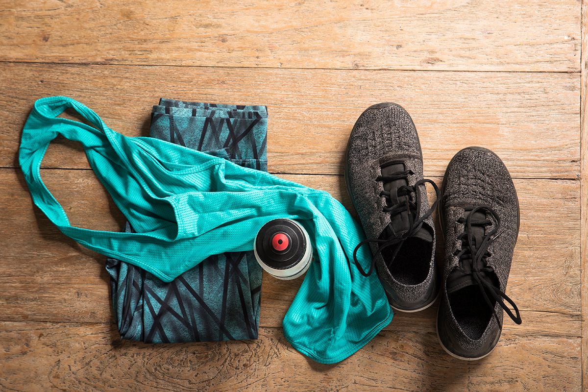 Sports clothes, running trainers and a water bottle on a wooden floor
