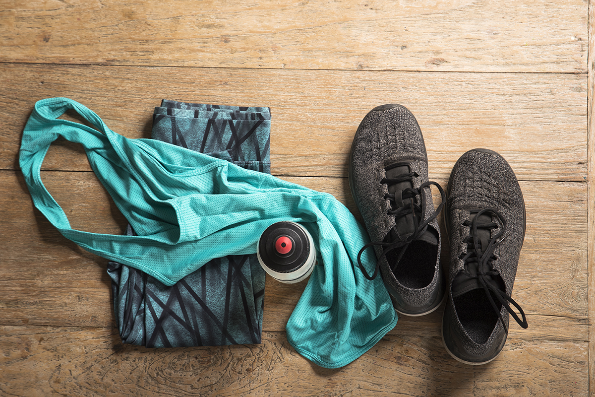 Sports clothes, running trainers and a water bottle on a wooden floor