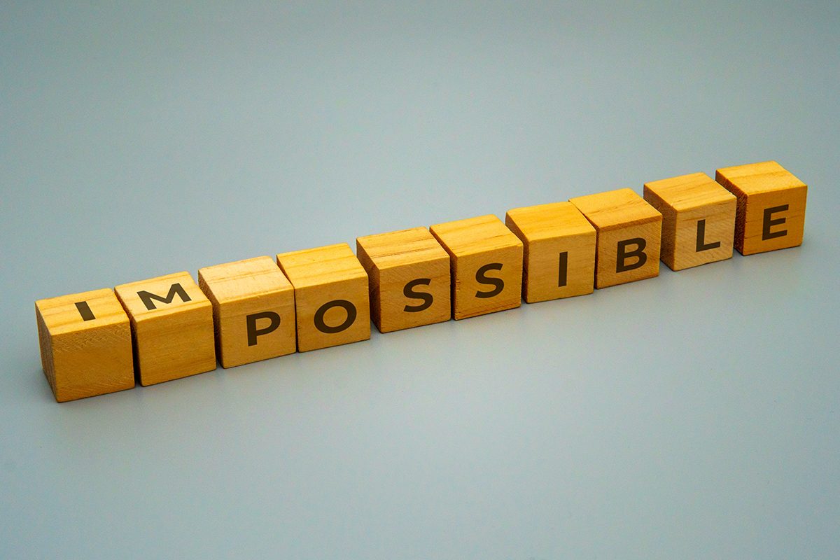 Wooden blocks with letters that spell out 'IMPOSSIBLE' are arranged to spell 'POSSIBLE'