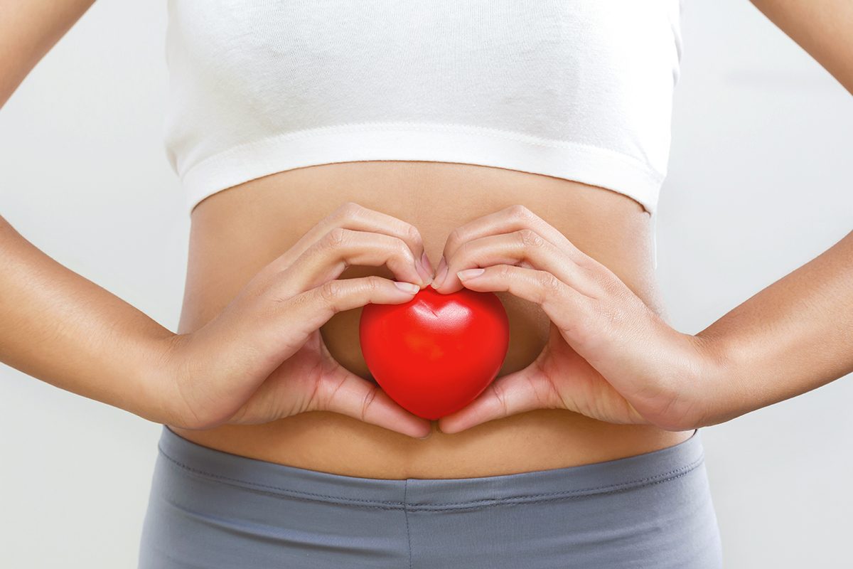 A woman holding a heart against her stomach