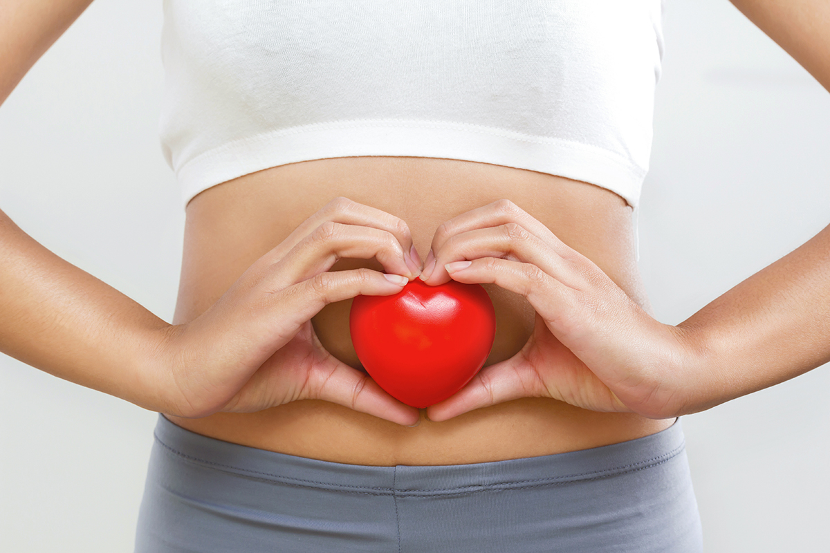 A woman holding a heart against her stomach
