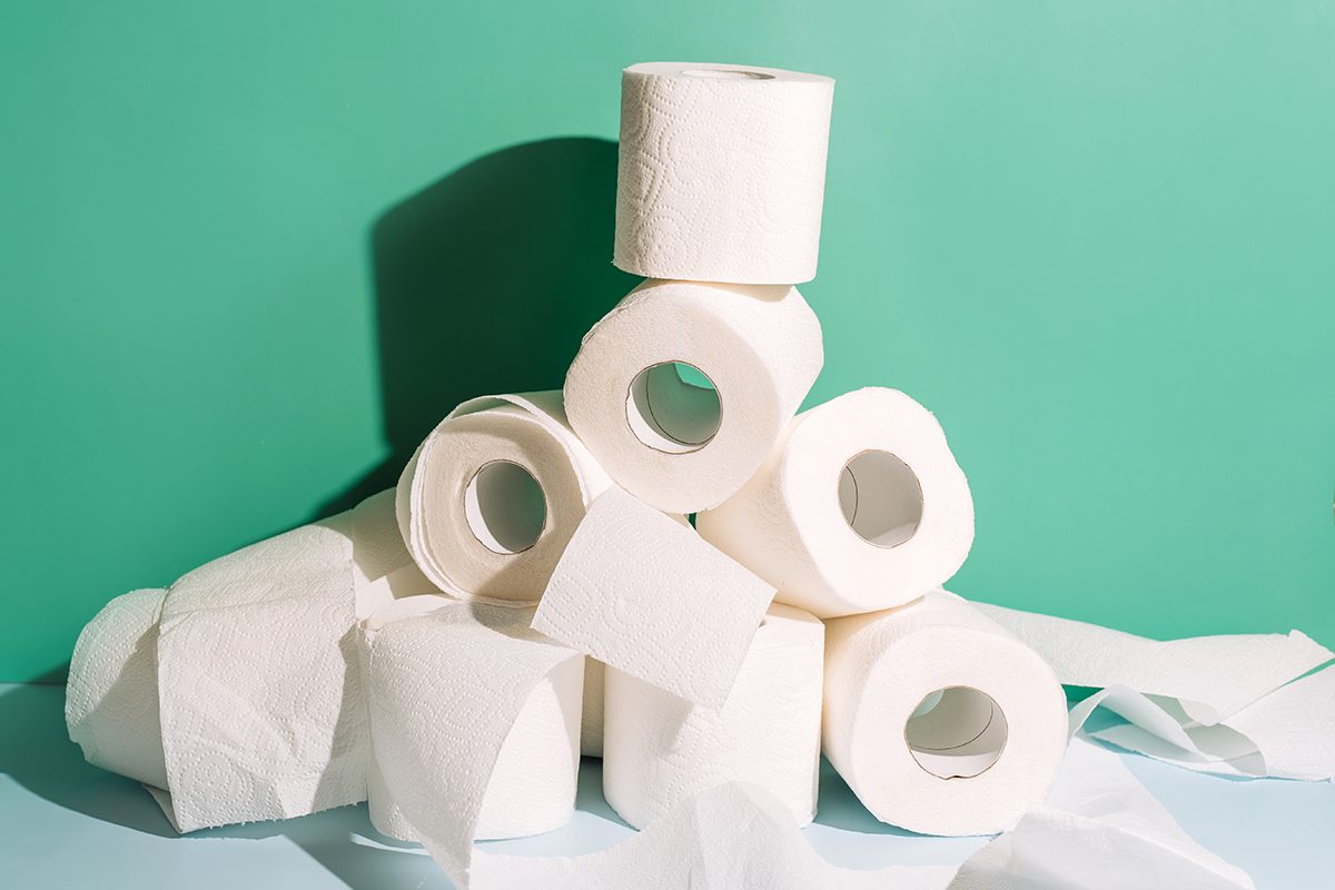 A pile of rolls of toilet paper against a green background
