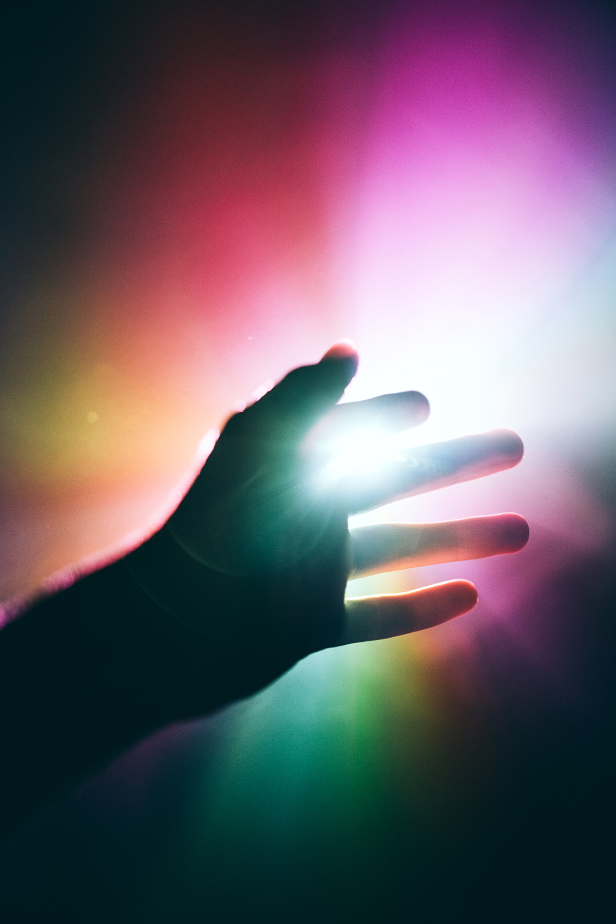 A hand reaching towards a multicoloured light