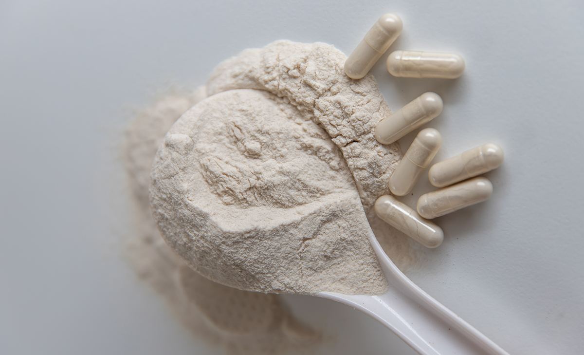 A spoon covered in powder next to some psyllium capsules.