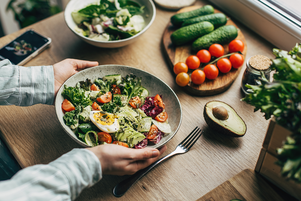 Hands hold a bowl of salad.