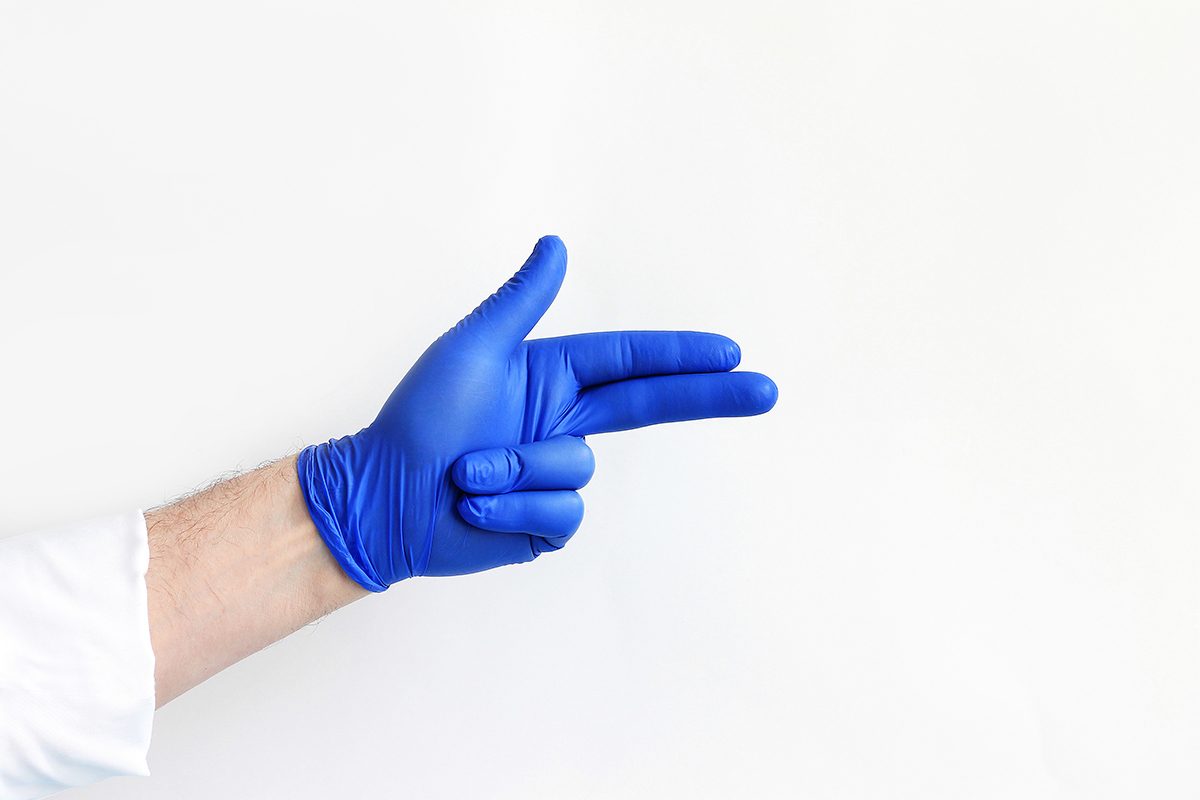 A doctor's hand in blue medical glove is positioned against a white background.