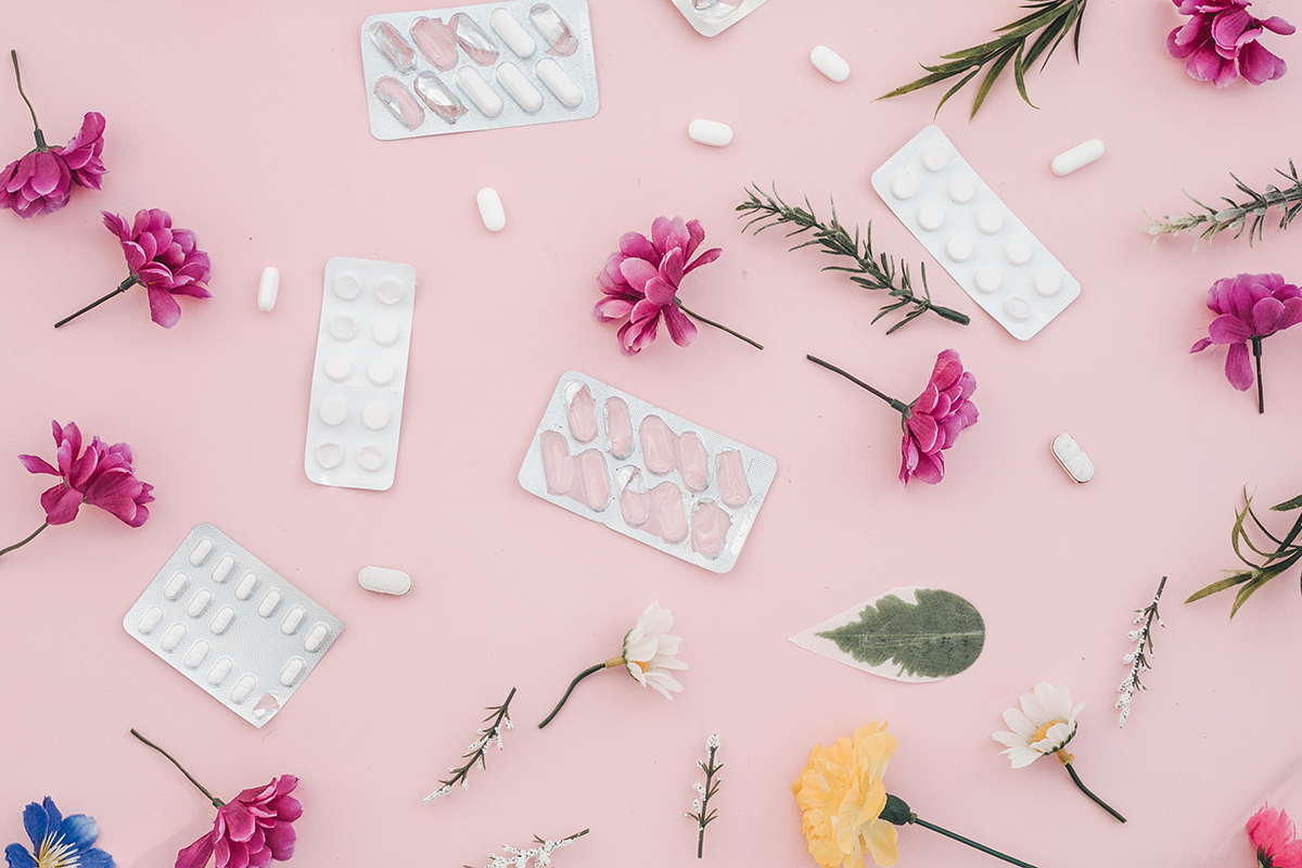 Pills and flowers on a pink background