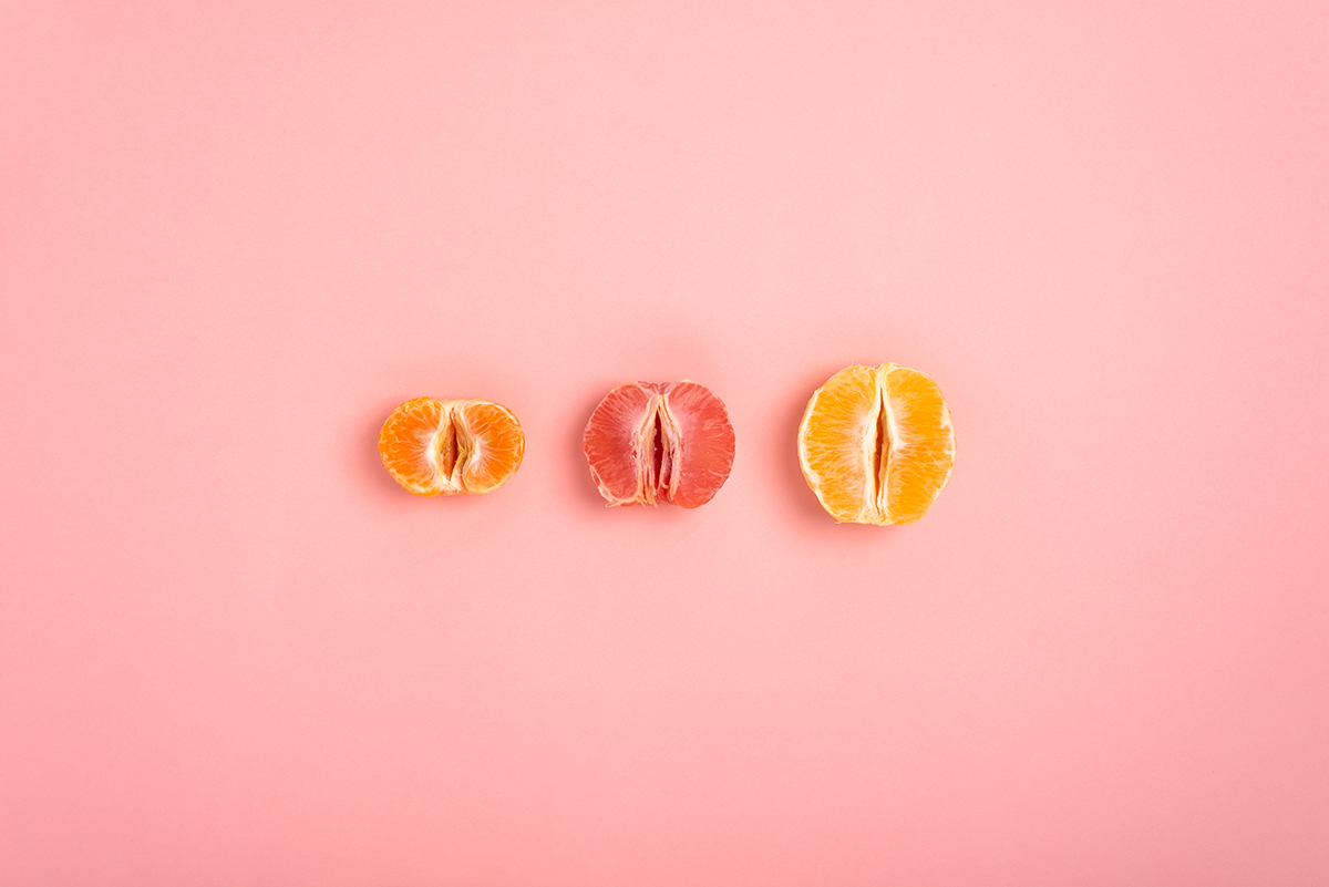 Half of a satsuma, grapefruit and orange on a pink background