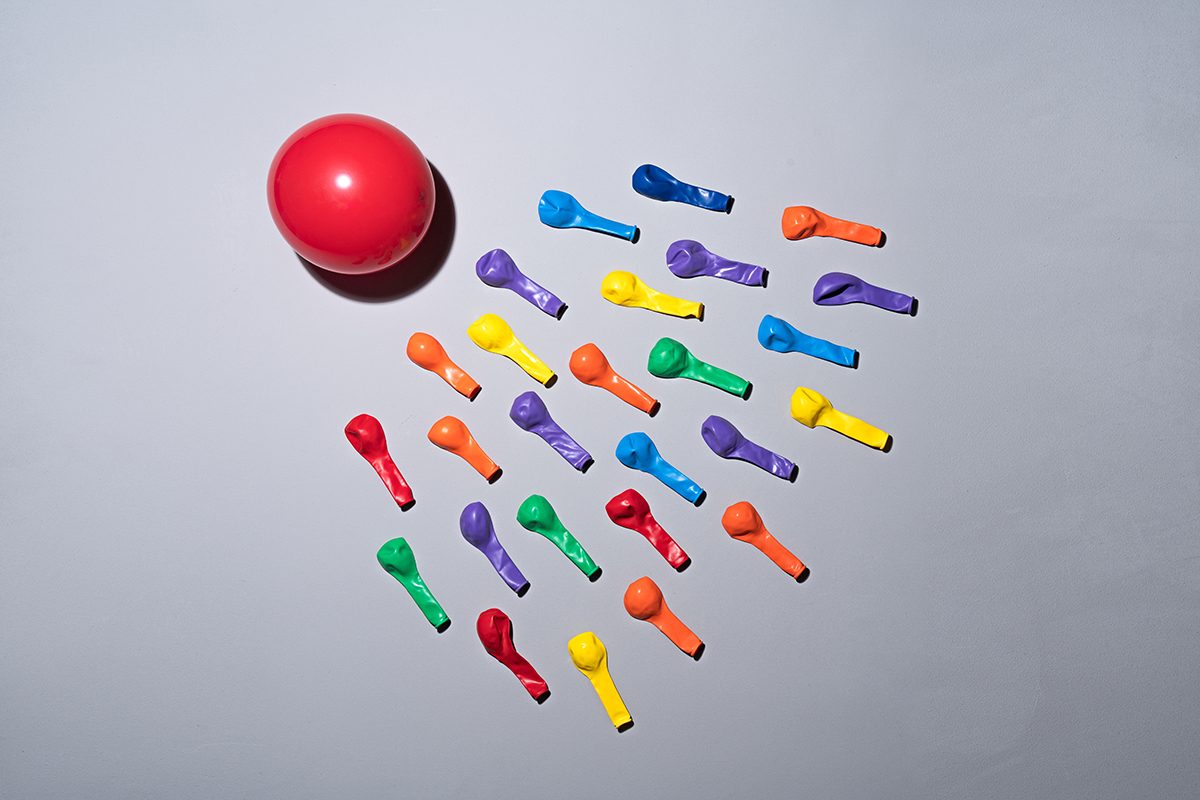 Uninflated colourful latex balloons are next to a ball to symbolise insemination